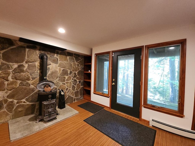 entryway featuring hardwood / wood-style flooring, a wood stove, and baseboard heating