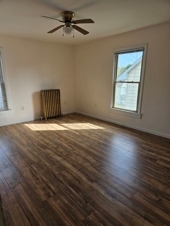 empty room with ceiling fan, radiator heating unit, and dark hardwood / wood-style flooring