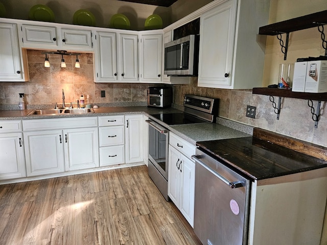 kitchen with sink, stainless steel appliances, tasteful backsplash, white cabinets, and light wood-type flooring