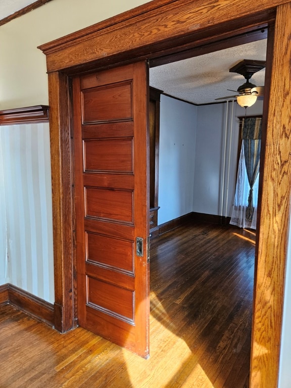 hall with wood-type flooring and a textured ceiling