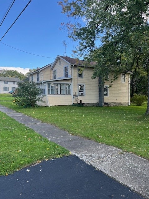 view of home's exterior with a sunroom and a lawn