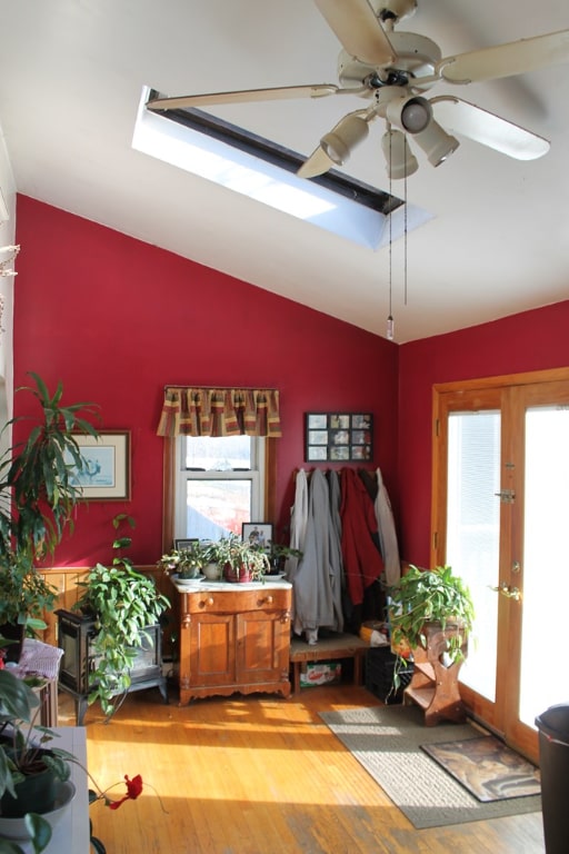 interior space with hardwood / wood-style flooring, lofted ceiling with skylight, ceiling fan, and french doors