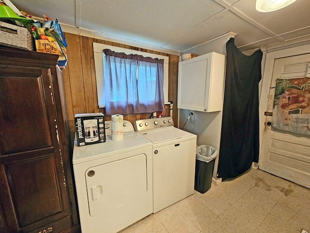 laundry room featuring cabinets, washing machine and dryer, and wood walls