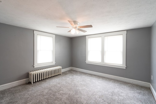 carpeted spare room featuring radiator, a textured ceiling, and ceiling fan