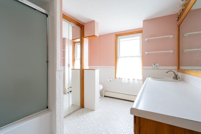 full bathroom with combined bath / shower with glass door, a baseboard radiator, tile walls, vanity, and toilet