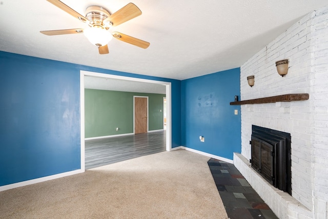 unfurnished living room featuring a brick fireplace, ceiling fan, a textured ceiling, and carpet