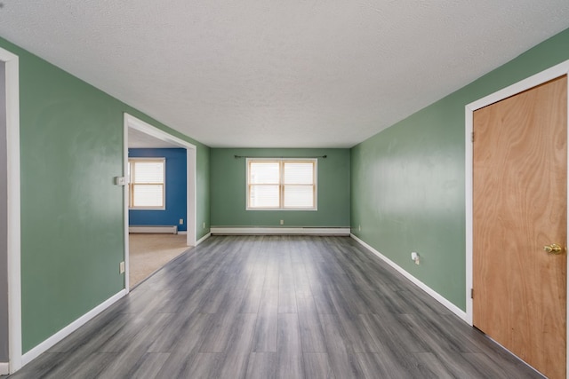 spare room featuring a baseboard heating unit, dark hardwood / wood-style floors, and a textured ceiling