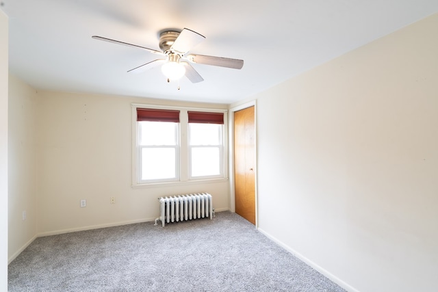 carpeted empty room featuring radiator heating unit and ceiling fan