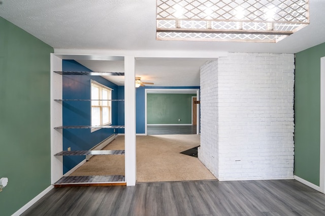 empty room featuring dark hardwood / wood-style flooring, ceiling fan, a textured ceiling, and brick wall