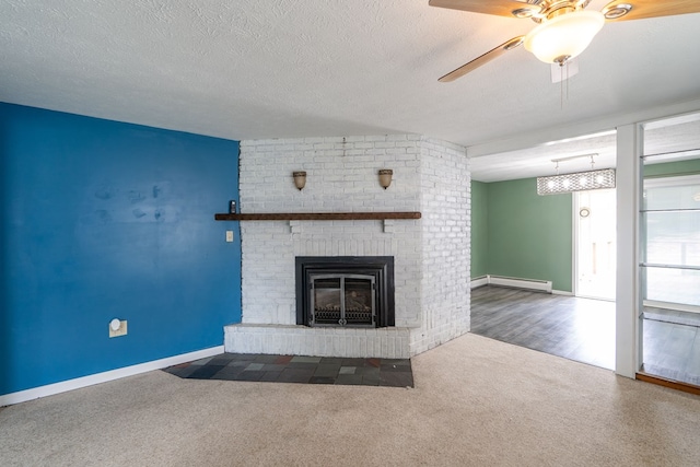 unfurnished living room featuring ceiling fan, dark colored carpet, a textured ceiling, a brick fireplace, and a baseboard radiator