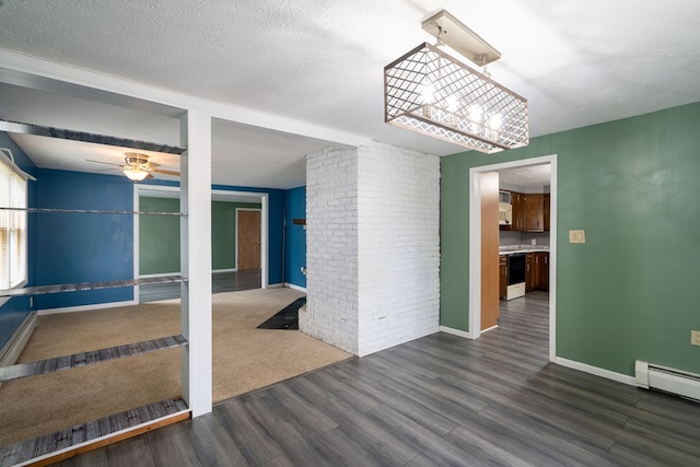 spare room featuring brick wall, dark hardwood / wood-style floors, a baseboard heating unit, ceiling fan, and a textured ceiling