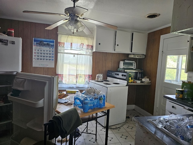 kitchen with wood walls, washer / clothes dryer, white cabinets, ornamental molding, and ceiling fan