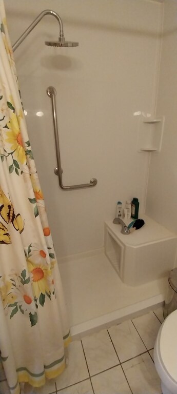 bathroom with tile patterned flooring, toilet, and a shower with shower curtain