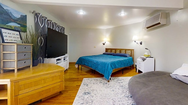 bedroom featuring hardwood / wood-style flooring and an AC wall unit