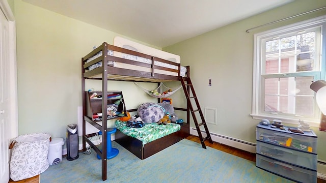 bedroom with a baseboard radiator and hardwood / wood-style floors