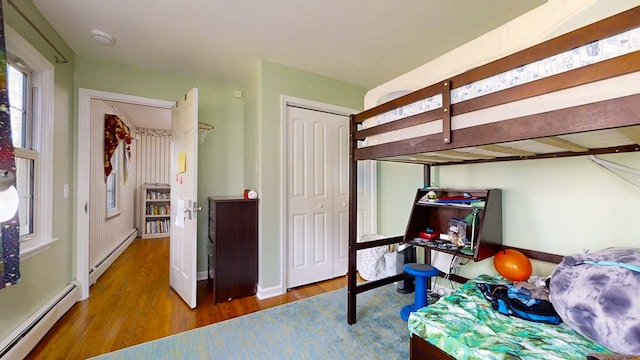 bedroom with hardwood / wood-style flooring, a baseboard radiator, and a closet