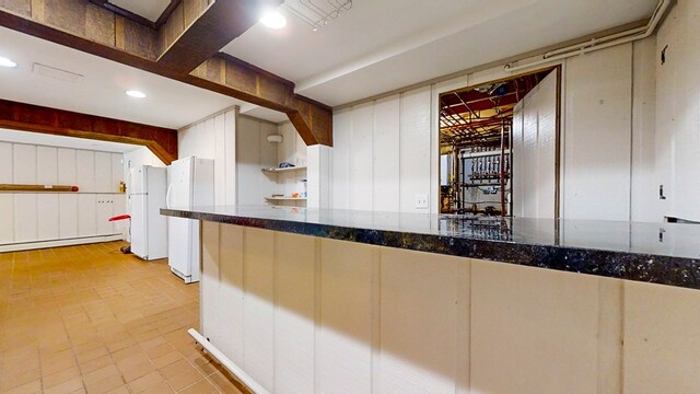 kitchen with white refrigerator, dark stone countertops, and a baseboard heating unit