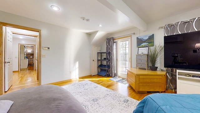 bedroom with light hardwood / wood-style floors and beamed ceiling