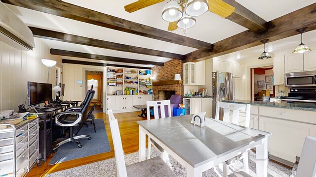 interior space with beamed ceiling, ceiling fan, wooden walls, and light hardwood / wood-style floors