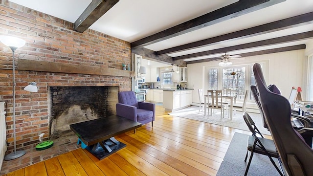 living room featuring a brick fireplace, light hardwood / wood-style flooring, and beamed ceiling