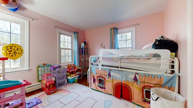 bedroom with wood-type flooring and a baseboard heating unit