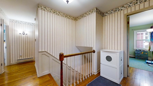 corridor featuring a baseboard heating unit and hardwood / wood-style floors