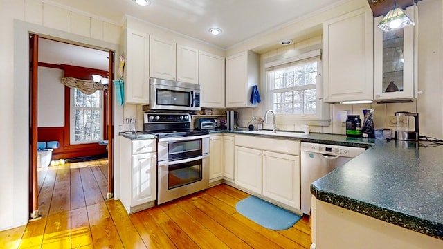 kitchen with sink, light hardwood / wood-style flooring, appliances with stainless steel finishes, ornamental molding, and white cabinets