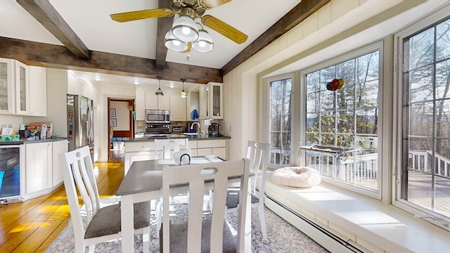 dining area featuring sink, light wood-type flooring, wine cooler, a baseboard heating unit, and beam ceiling