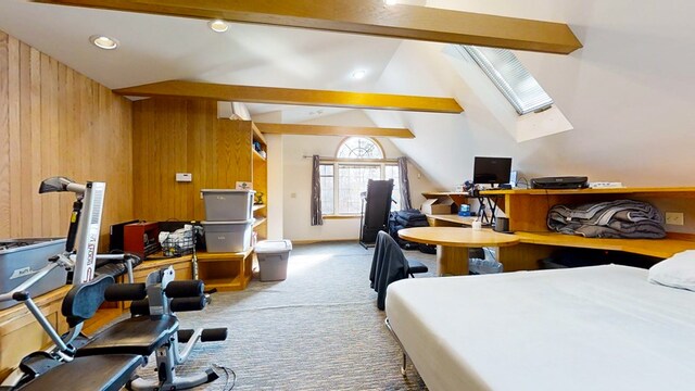 carpeted bedroom with wooden walls and lofted ceiling with skylight