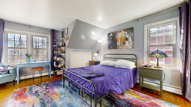 bedroom featuring a baseboard heating unit, vaulted ceiling, and wood-type flooring