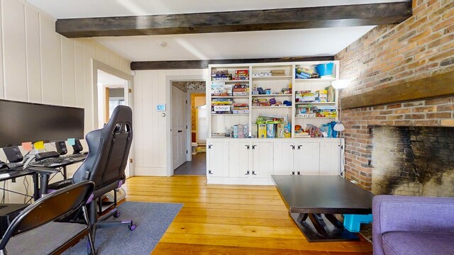 office area with beam ceiling, wooden walls, and light wood-type flooring