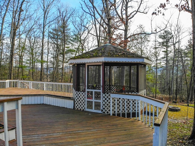 wooden terrace featuring a gazebo, a fire pit, and a sunroom