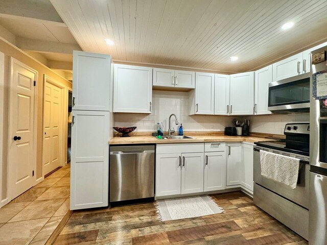 kitchen with stainless steel appliances, white cabinetry, sink, and backsplash