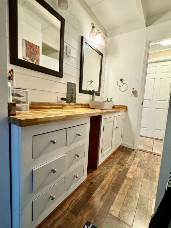 bathroom with vanity, hardwood / wood-style flooring, and wooden walls