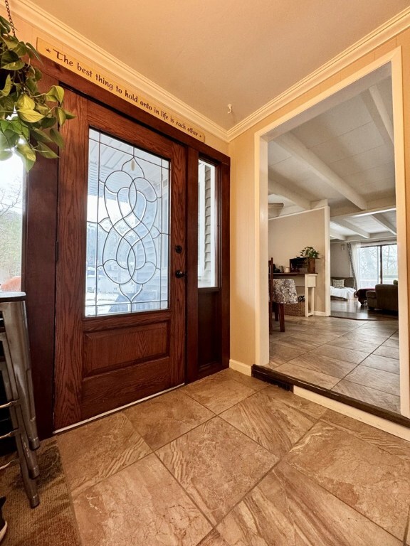 entryway with crown molding and beam ceiling