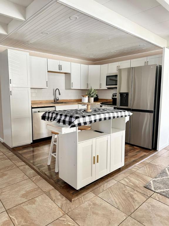 kitchen with appliances with stainless steel finishes, butcher block countertops, white cabinetry, a breakfast bar area, and backsplash