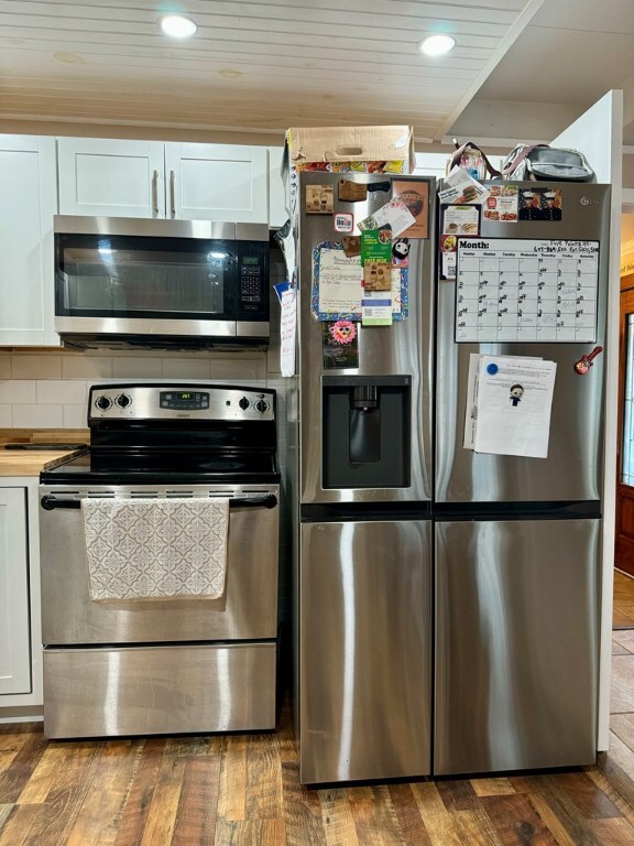 kitchen featuring appliances with stainless steel finishes, white cabinetry, backsplash, and hardwood / wood-style flooring