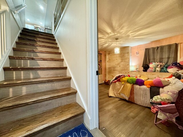 staircase featuring wood-type flooring and wooden walls