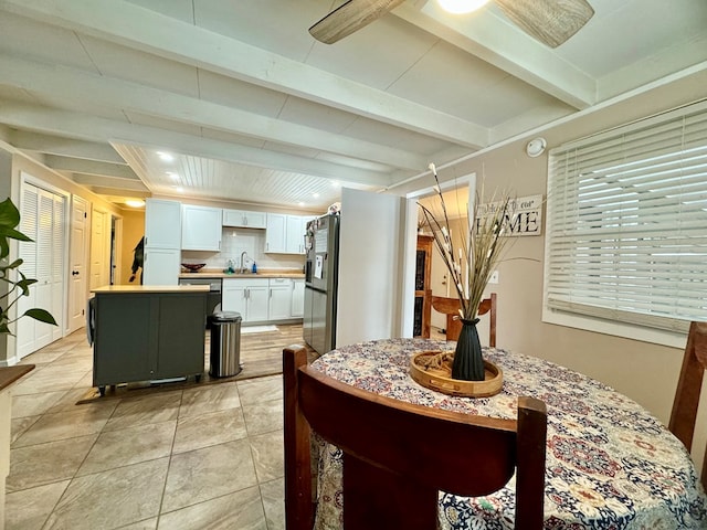 dining area featuring beamed ceiling, light tile patterned flooring, and sink