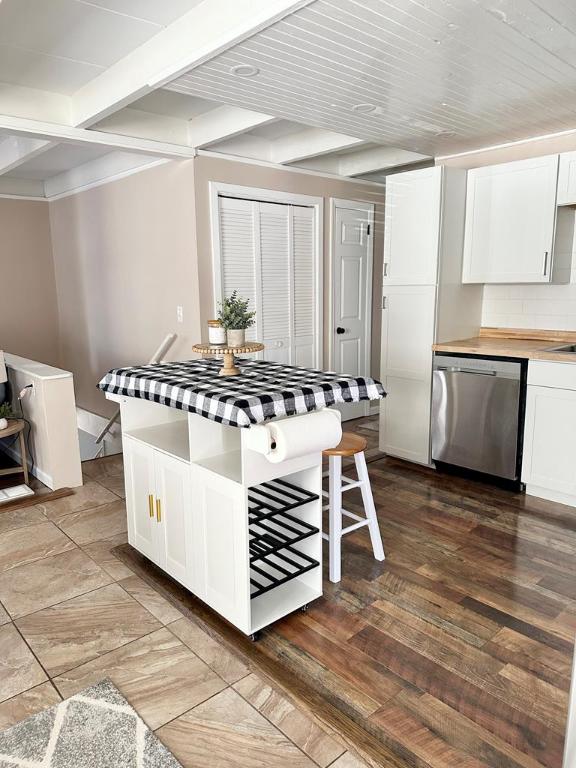 kitchen featuring tasteful backsplash, stainless steel dishwasher, white cabinets, and beam ceiling