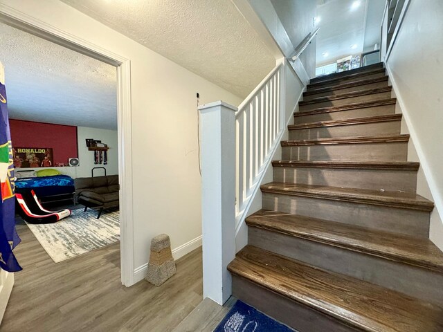 stairs featuring hardwood / wood-style floors and a textured ceiling