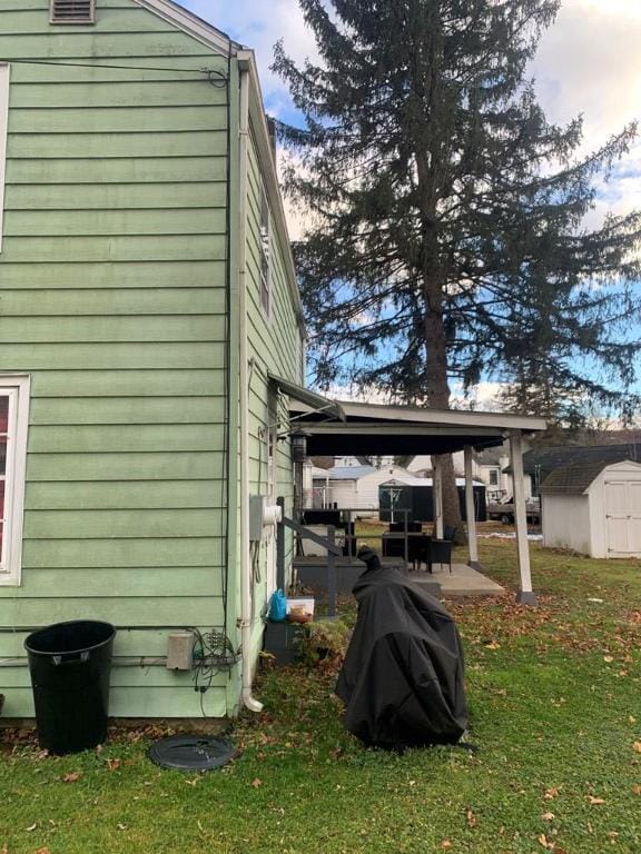 view of side of property featuring a shed, a yard, and a patio