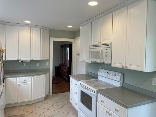 kitchen with white appliances, light tile patterned floors, and white cabinets