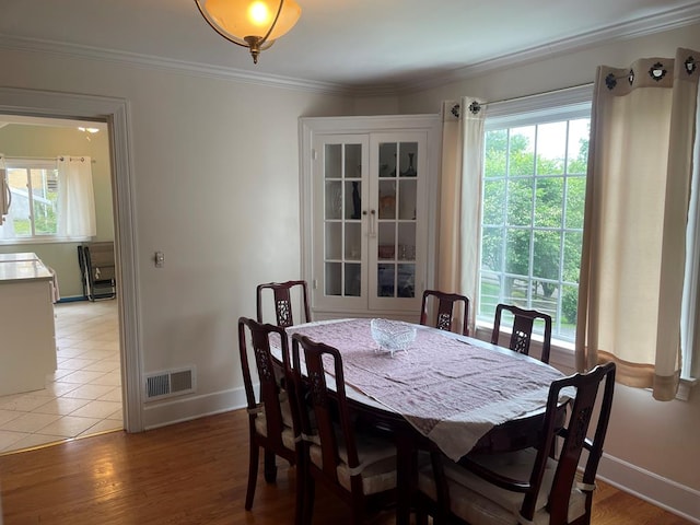 dining area with hardwood / wood-style flooring, crown molding, and plenty of natural light