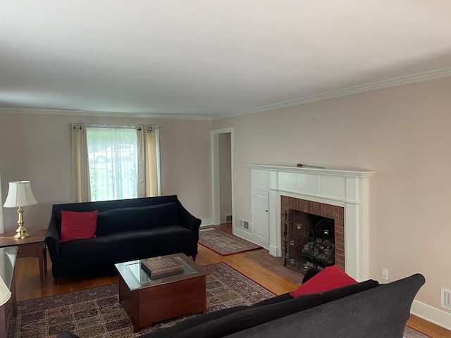 living room featuring hardwood / wood-style flooring, crown molding, and a brick fireplace