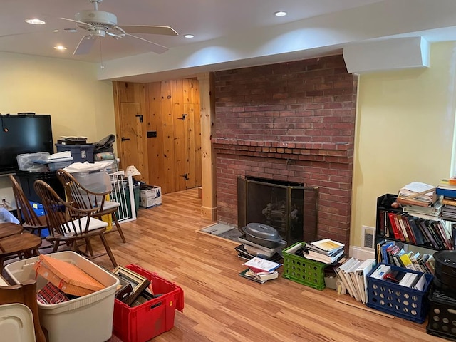 office space featuring ceiling fan, light hardwood / wood-style floors, and a brick fireplace