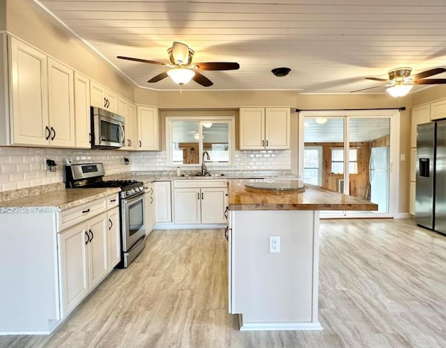 kitchen with white cabinetry, stainless steel appliances, a center island, tasteful backsplash, and light wood-type flooring