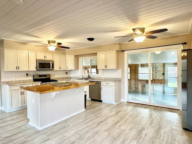 kitchen featuring butcher block counters, a center island, stainless steel appliances, light hardwood / wood-style floors, and white cabinets