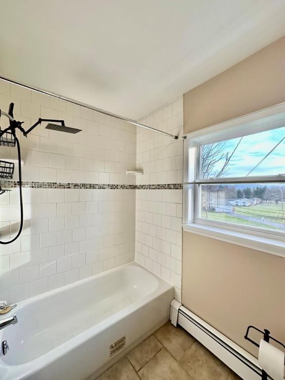 bathroom featuring tile patterned flooring, tiled shower / bath, and a baseboard heating unit