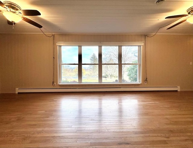 unfurnished room featuring ceiling fan, hardwood / wood-style floors, and baseboard heating